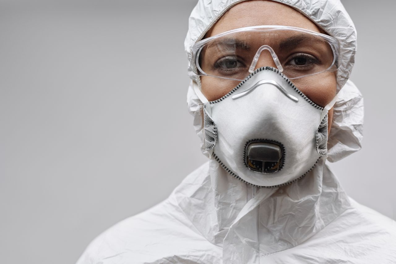 Close-up of a person wearing protective clothing, safety goggles, and a respirator mask.