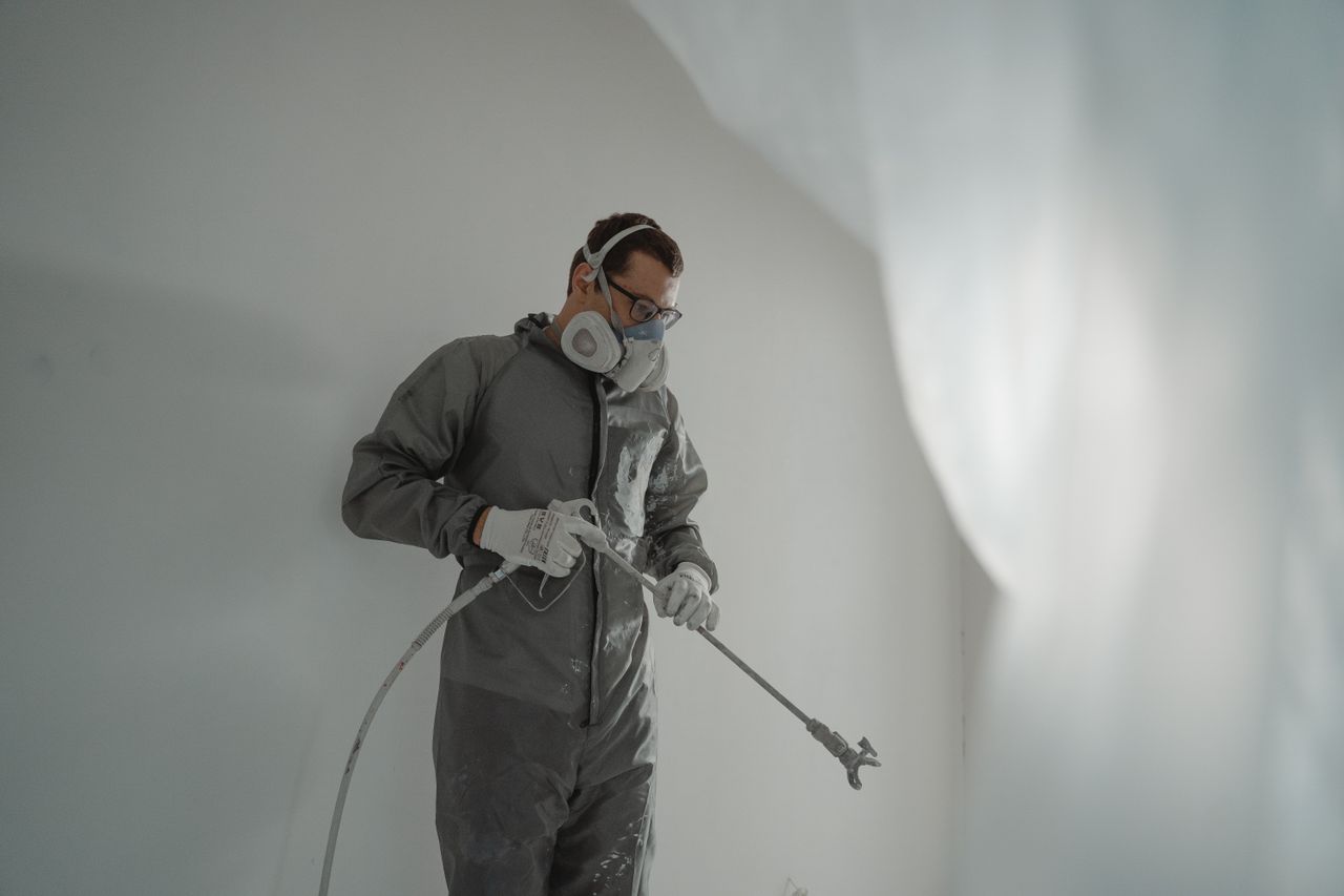 Person in protective gear painting a wall, showcasing house renovation work.